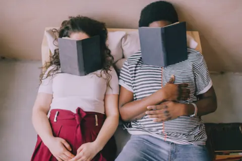 couple-sitting-chair-sleeping-with-books-their-faces