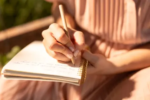 close-up-hand-writing-notebook-23-2148973424
